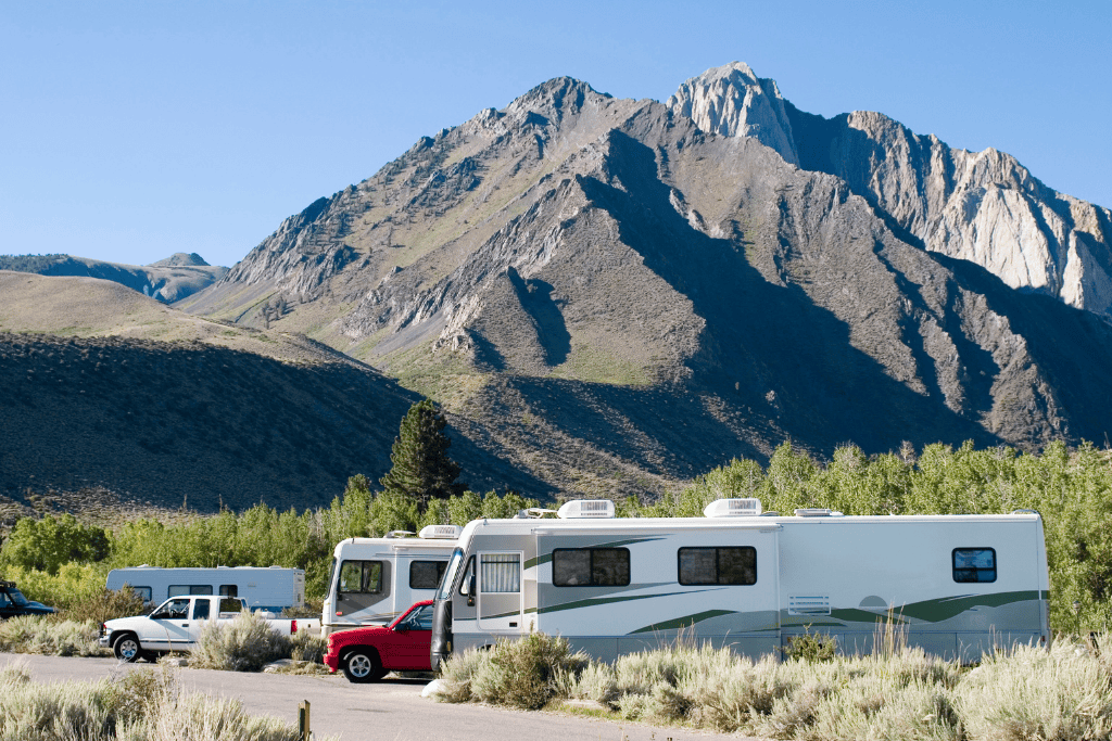 RV's and trucks parked in the desert with a mountain in the background. 